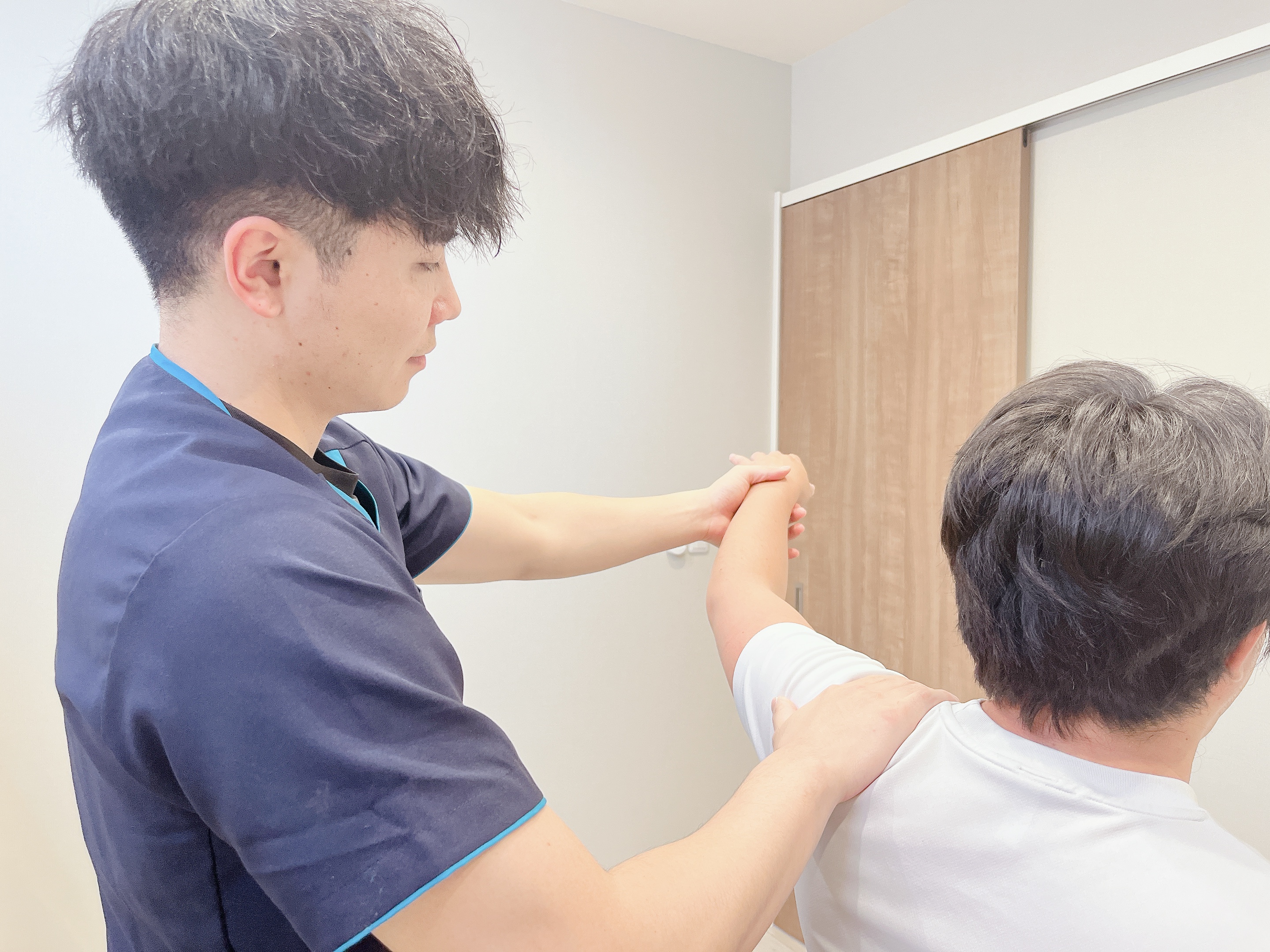 肩の動きや痛みの角度を確認する施術の様子